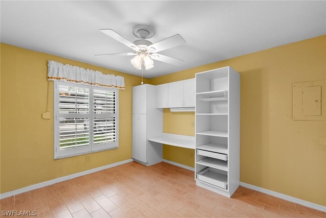 unfurnished bedroom with light wood-style floors, electric panel, baseboards, and a ceiling fan