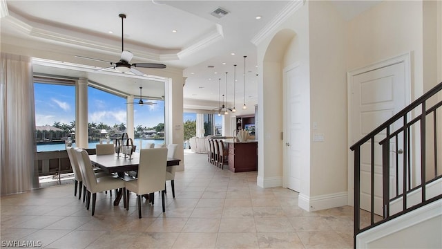 tiled dining space featuring crown molding, a water view, and a raised ceiling