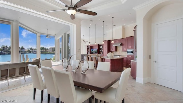 dining room featuring ceiling fan, a water view, and ornamental molding