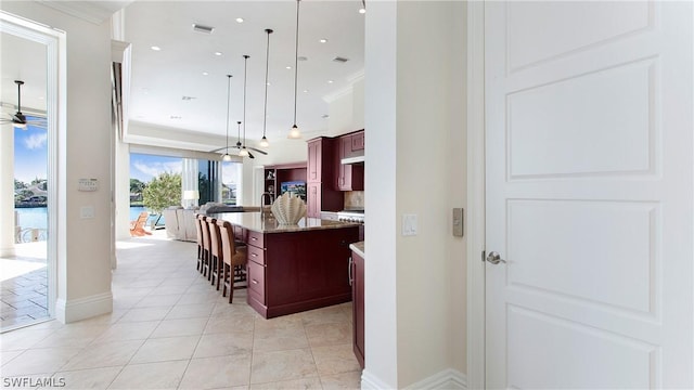 kitchen with a center island, ornamental molding, ceiling fan, a breakfast bar area, and hanging light fixtures