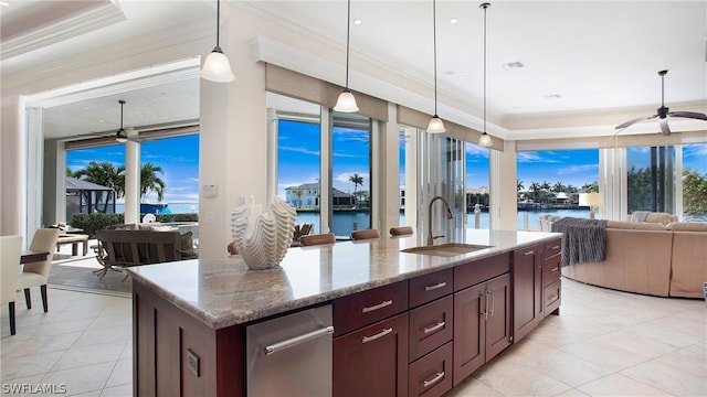 kitchen featuring decorative light fixtures, a raised ceiling, a kitchen island with sink, and a water view