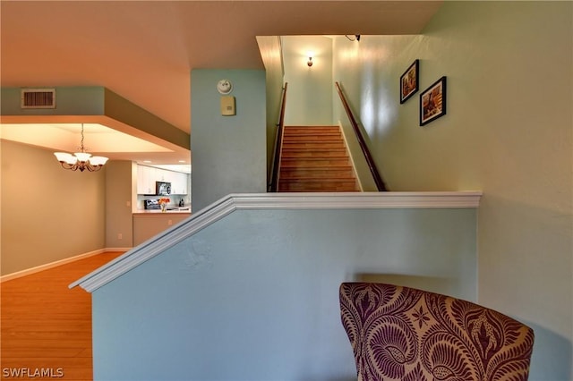 staircase with wood-type flooring and a chandelier