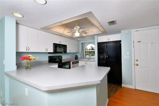 kitchen featuring kitchen peninsula, white cabinets, light hardwood / wood-style floors, and black appliances