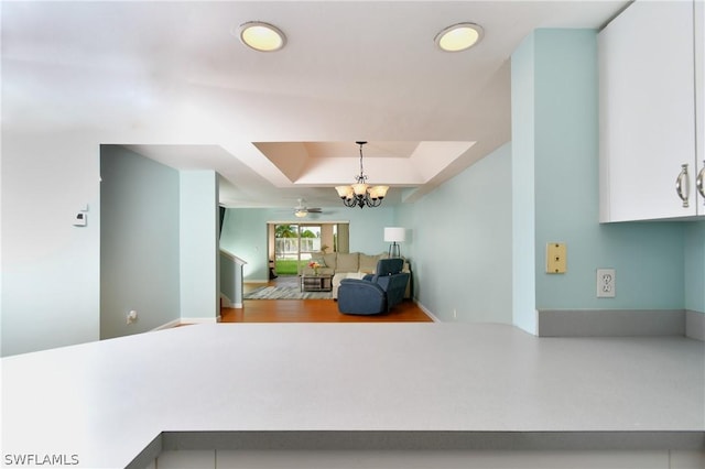 interior space featuring hanging light fixtures, white cabinets, a chandelier, and a tray ceiling