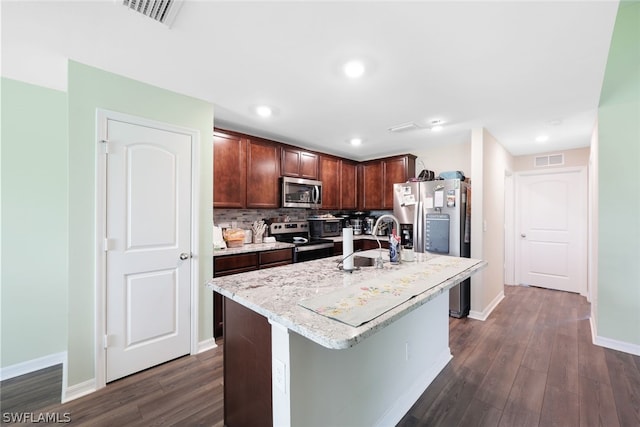 kitchen featuring stainless steel appliances, sink, backsplash, an island with sink, and dark hardwood / wood-style flooring