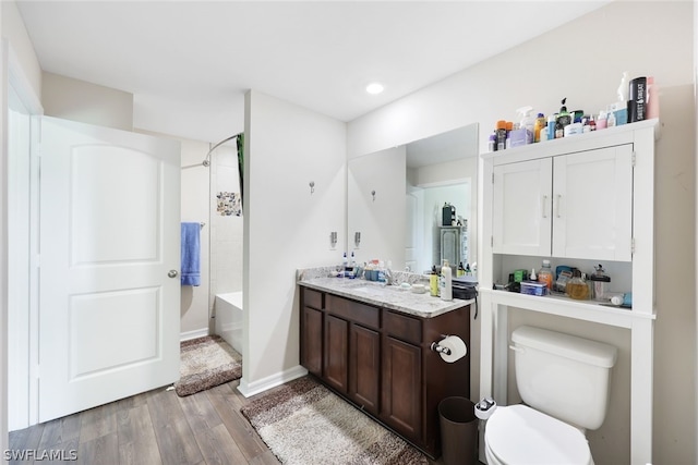 full bathroom featuring vanity, tiled shower / bath combo, toilet, and hardwood / wood-style floors