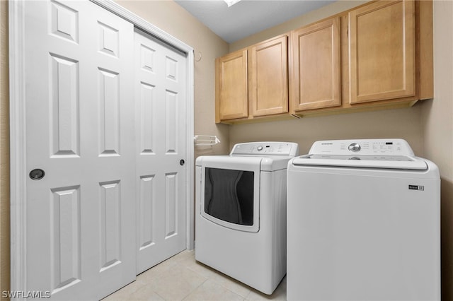 washroom with washer and clothes dryer, cabinets, and light tile patterned flooring