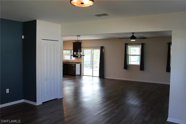 unfurnished living room featuring dark wood-type flooring and ceiling fan