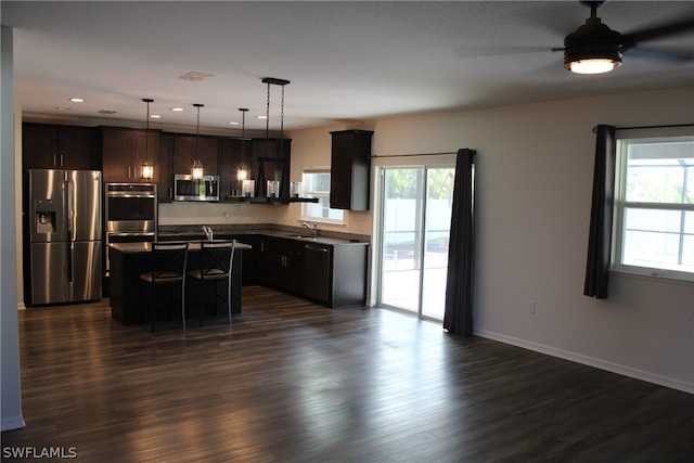 kitchen with dark hardwood / wood-style floors, stainless steel appliances, hanging light fixtures, and a center island