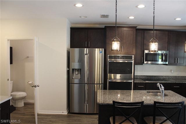 kitchen featuring a breakfast bar, dark hardwood / wood-style flooring, stainless steel appliances, stone countertops, and sink