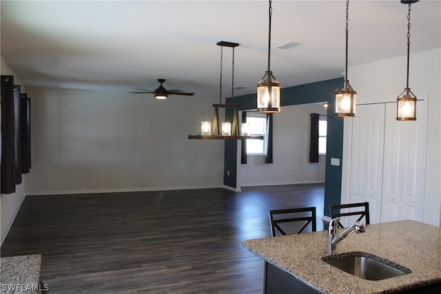 kitchen featuring sink, pendant lighting, dark hardwood / wood-style floors, light stone countertops, and ceiling fan