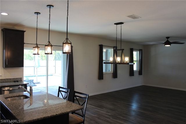 kitchen with dark stone counters, sink, decorative light fixtures, dark hardwood / wood-style flooring, and ceiling fan