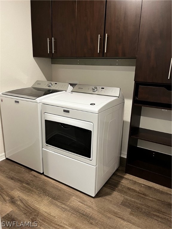 laundry room featuring independent washer and dryer, wood-type flooring, and cabinets