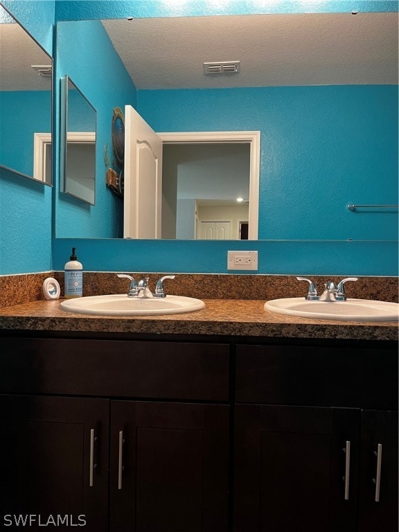 bathroom featuring double vanity and a textured ceiling