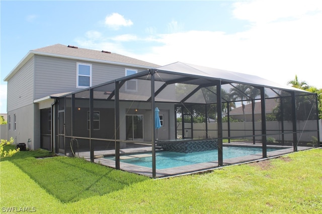 rear view of house with a lanai, a lawn, and a fenced in pool