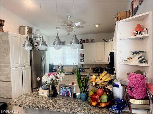 kitchen with white cabinets, stainless steel fridge, sink, stone countertops, and ceiling fan