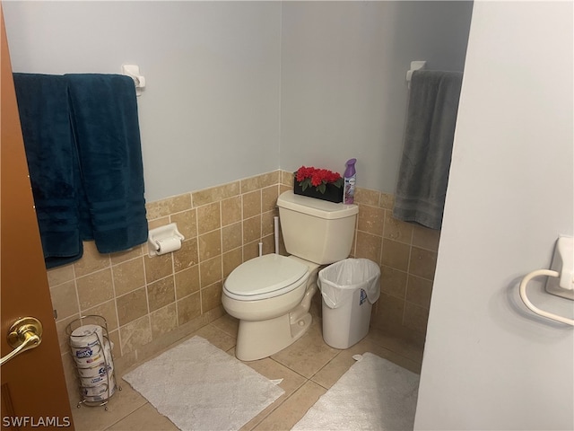 bathroom featuring toilet, tile patterned flooring, and tile walls