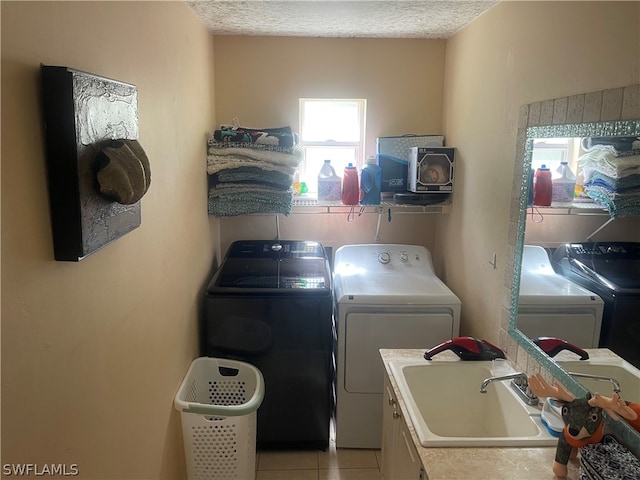 clothes washing area featuring sink, cabinets, a textured ceiling, independent washer and dryer, and light tile patterned flooring