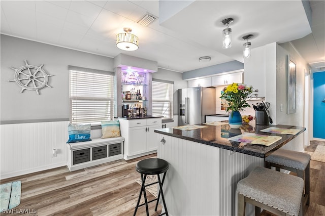 kitchen featuring high end refrigerator, a kitchen breakfast bar, white cabinets, and light hardwood / wood-style floors