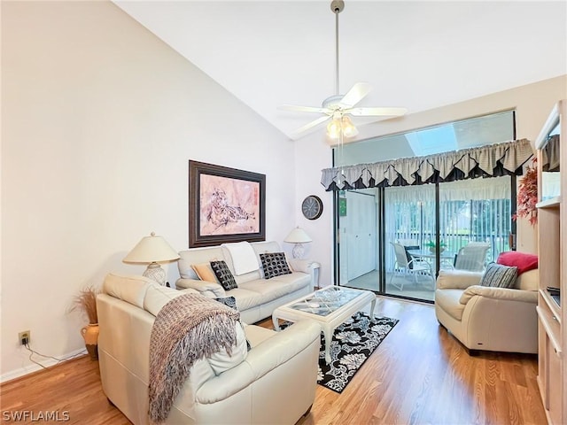 living room featuring ceiling fan, lofted ceiling with skylight, and light hardwood / wood-style flooring