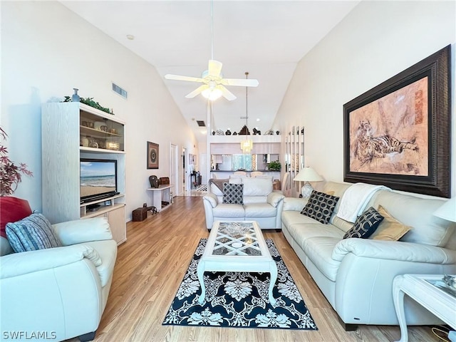 living room with light hardwood / wood-style flooring, high vaulted ceiling, and ceiling fan