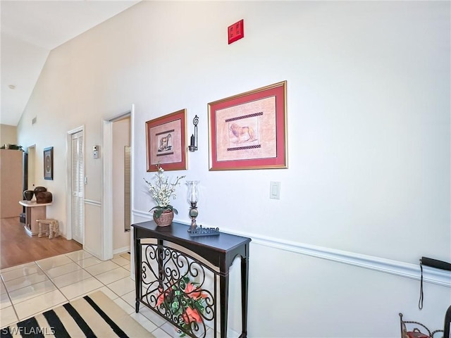 corridor with light tile patterned flooring and vaulted ceiling