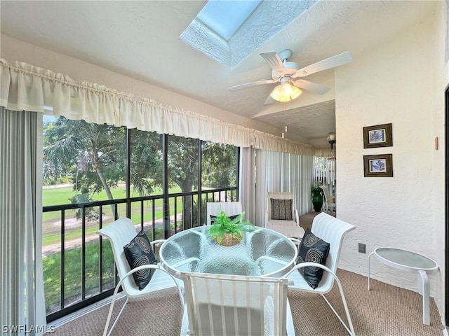 sunroom / solarium featuring lofted ceiling with skylight and ceiling fan