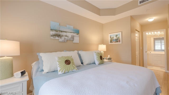 bedroom with connected bathroom and hardwood / wood-style floors