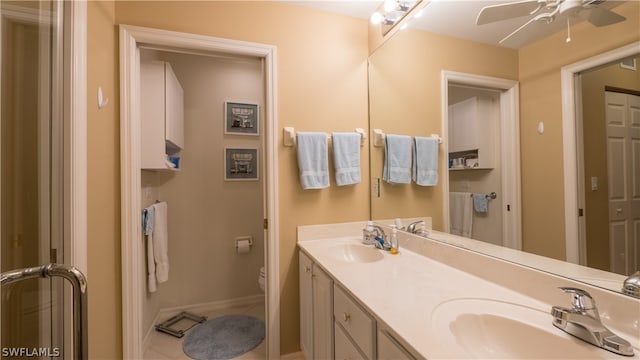 bathroom with tile patterned floors, ceiling fan, toilet, and dual bowl vanity