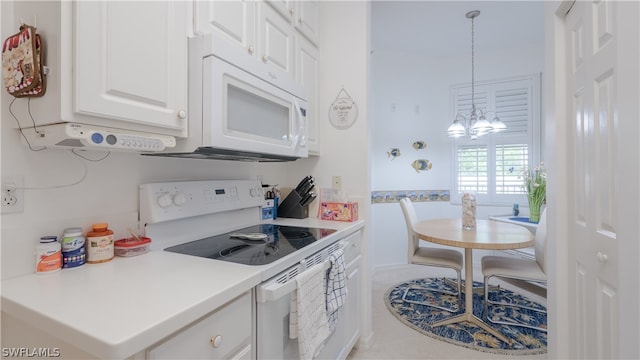 kitchen featuring white cabinetry, a notable chandelier, hanging light fixtures, and white appliances