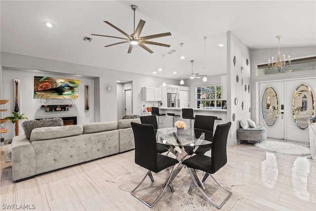 dining room with ceiling fan with notable chandelier, lofted ceiling, and light tile patterned floors