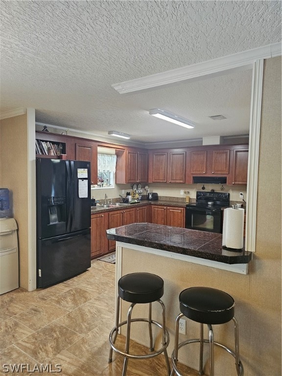 kitchen featuring a kitchen bar, kitchen peninsula, black appliances, and a textured ceiling