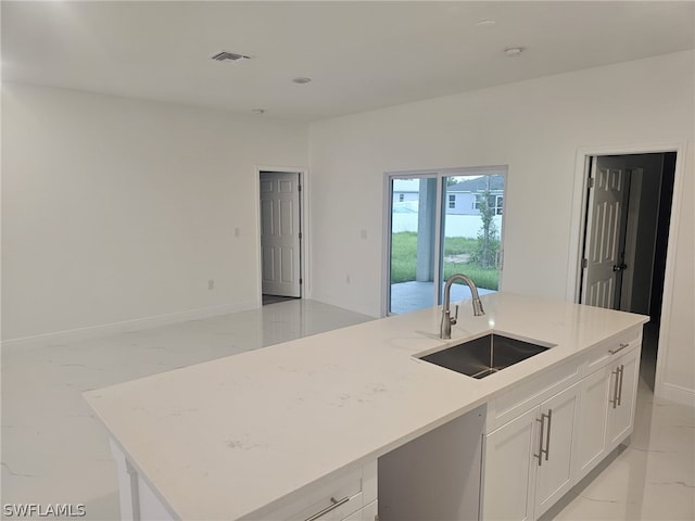 kitchen with marble finish floor, visible vents, a kitchen island with sink, a sink, and white cabinetry