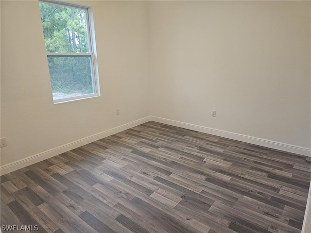 unfurnished room with dark wood-type flooring and baseboards