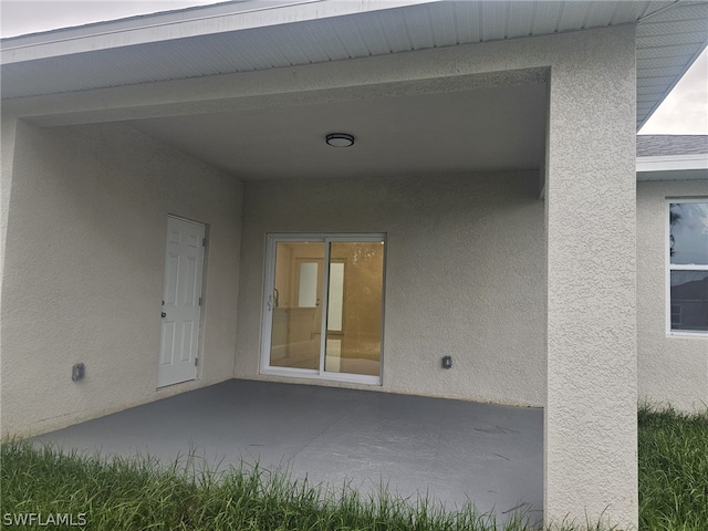 entrance to property featuring a patio and stucco siding