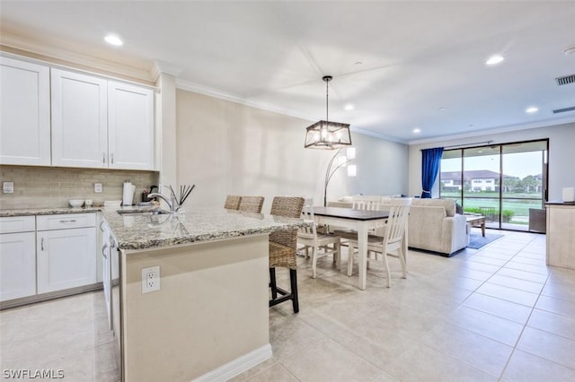 kitchen with white cabinets, a center island, decorative light fixtures, a breakfast bar, and light tile patterned floors