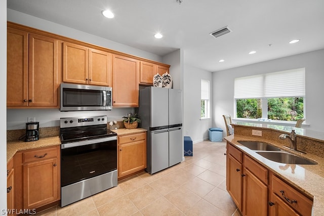 kitchen featuring light stone counters, stainless steel appliances, light tile patterned flooring, and sink