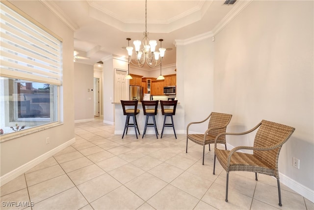 dining space with light tile patterned flooring, crown molding, and a tray ceiling