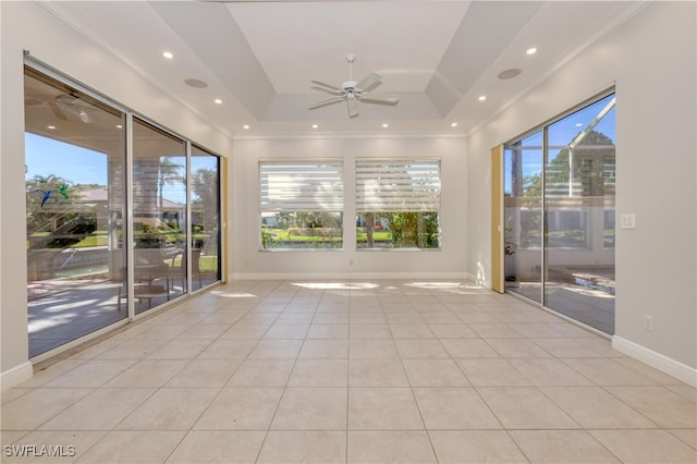 tiled spare room featuring a tray ceiling, a wealth of natural light, and ceiling fan