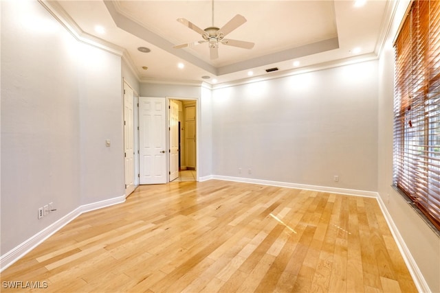 spare room featuring ceiling fan, ornamental molding, a raised ceiling, and light hardwood / wood-style floors