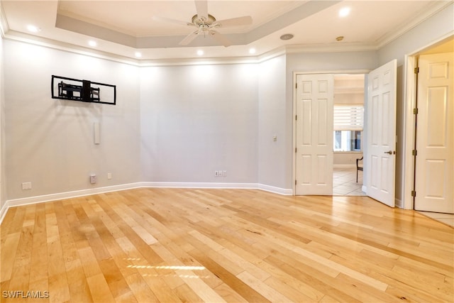 spare room featuring ornamental molding, a raised ceiling, ceiling fan, and light wood-type flooring