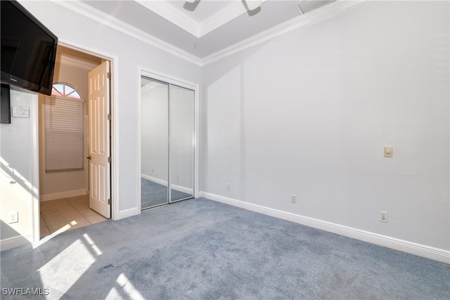 unfurnished bedroom featuring crown molding, light colored carpet, ceiling fan, and a closet