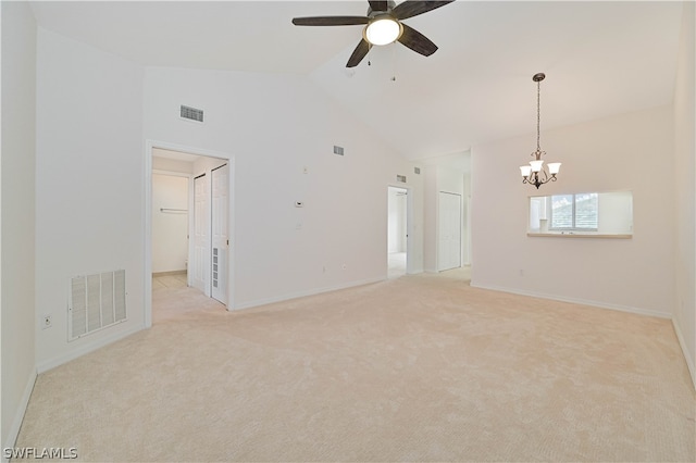 carpeted spare room featuring ceiling fan with notable chandelier and high vaulted ceiling