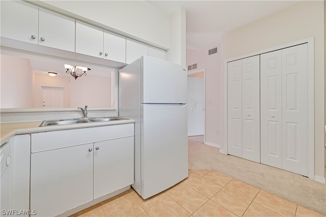 kitchen with white cabinetry, white fridge, a chandelier, light colored carpet, and sink