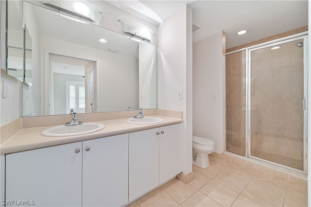 bathroom with tile patterned floors, a shower with door, toilet, and dual bowl vanity