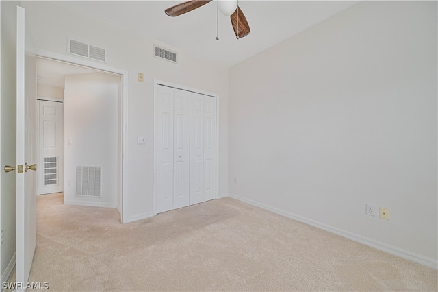 unfurnished bedroom with a closet, light colored carpet, and ceiling fan