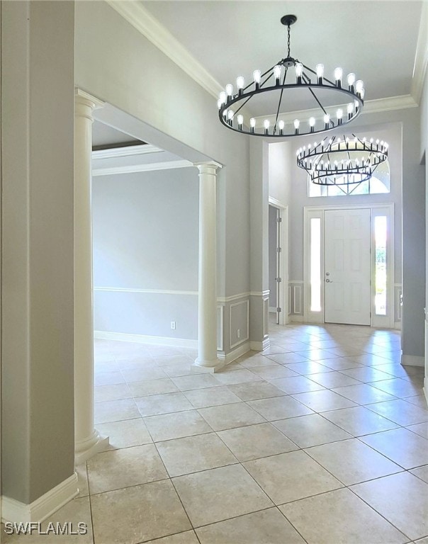 tiled foyer entrance featuring ornamental molding, ornate columns, and a chandelier