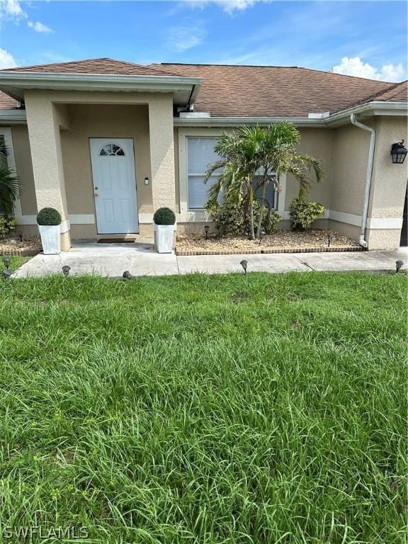212 Paxton St, Lehigh Acres, FL 33974 - entrance to property with stucco siding, a yard, and roof with shingles