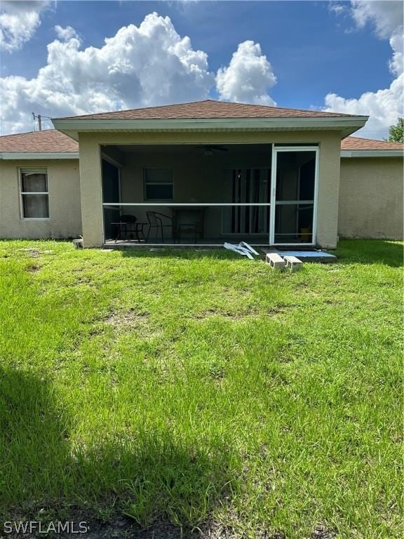 212 Paxton St, Lehigh Acres, FL 33974 - back of property with stucco siding, a lawn, a sunroom, and a shingled roof