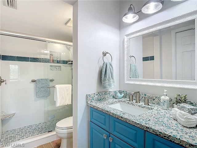 bathroom with hardwood / wood-style flooring, vanity, toilet, and a shower with door